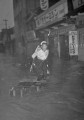 22６・２６熊本大水害　人通りは絶え濁流が町を支配し始めた。わが子を腰にくくり付けて歩くお母さん＝熊本市古桶屋町、26日午後4時ごろ