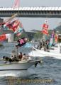 海上パレードで大漁旗をはためかせて港周辺を進む漁船団＝１８日午前、天草市