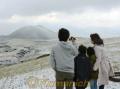 雪化粧した米塚に見入る観光客ら＝阿蘇市